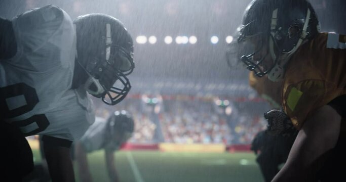 Portrait of Two Diverse American Football Teams Playing Ball with a Heavy Rain Forecast. Cinematic Footage of Strong Athletic Footballers in Professional Uniform Holding Each Other as the Game Starts
