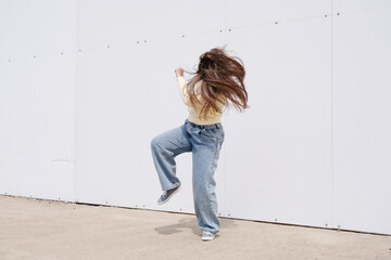 plus size woman wearing casual clothes dancing on white wall background in the street