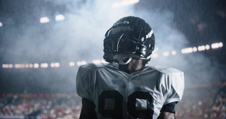 Powerful Portrait of an African American Football Player, Celebrating on the Field Under Stadium Lights in Rain. Intense and Inspirational Sports Footage with Dramatic Lighting and Weather Conditions