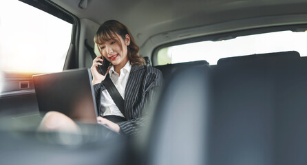 Businesswoman sitting in car back seats using smartphone  and  working on Digital Tablet. Female happy in car