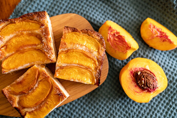 A dessert made of sliced peaches is on a wooden cutting board. The dessert is covered in sugar and looks delicious.