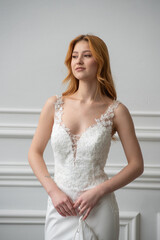 Fototapeta premium Beautiful young woman bride in fashion wedding dress in white interior