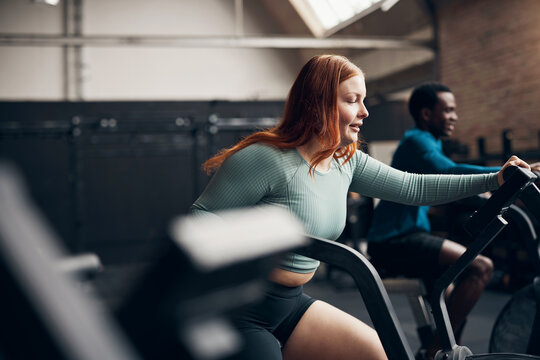 Young woman exercising on a stationary bike during a gym class