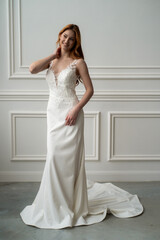 Fototapeta premium Beautiful young woman bride in fashion wedding dress in white interior