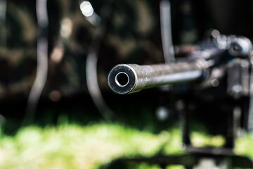 A close-up of the barrel of the machine gun in the summer. Blurred background.