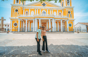 Two young tourists taking selfies in the cathedral of Granada, Nicaragua. Happy tourists taking selfies in a colorful colonial cathedral