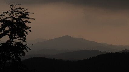 Beautiful view of mountains and trees during a sunset in Asian countryside with an upcoming rain and dark clouds