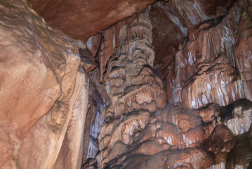 A cave with a lot of rock formations and a wall of brown rock.