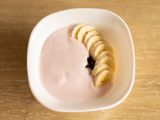 white plate with yogurt, bananas and granola