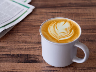 Hot latte coffee with latte art in grey ceramic mug on brown wooden table. .