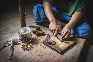 A man prepares marijuana on a cutting board to smoke, person who smokes drugs, drug addict, Drugs addiction and withdrawal symptoms concept. drugsInternational Day against Drug Abuse.