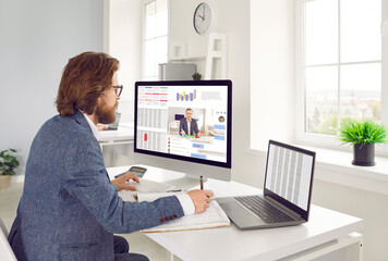 Serious busy man working on office computers. Businessman or financial accountant sitting at desk...