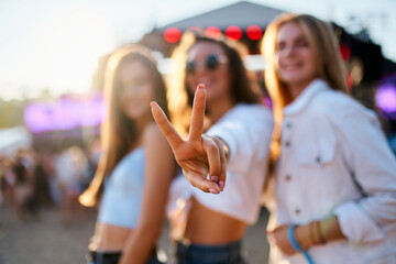 Group of female friends enjoy summer music festival on beach. Smiling girls in trendy outfits...
