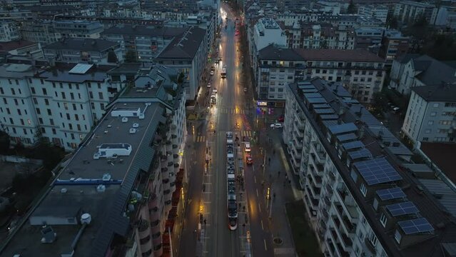 Aerial view of a central european city streets at dusk, featuring streetcar, car traffic, and residential buildings rooftops