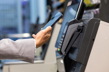 A person uses a smartphone for contactless payment at a store, offering convenience in retail with...