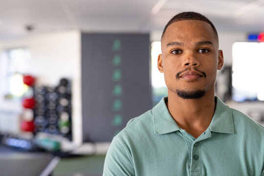 At gym rehabilitation center, young biracial male physical therapist wearing a green polo shirt stan