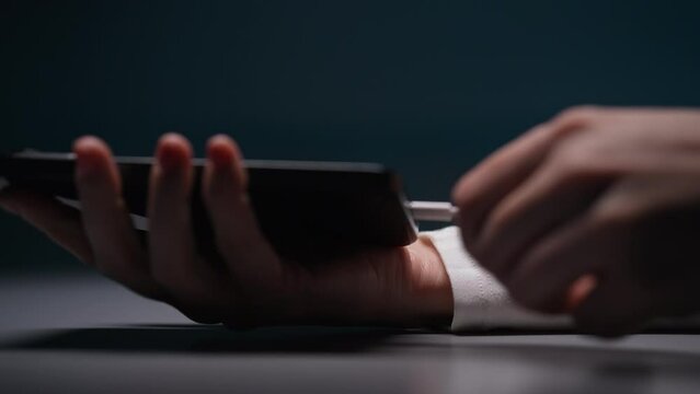 New mobile phone charging on table, female hand disconnecting unplug cable from smartphone. Girl holding cellphone in hand and disconnecting in charger cable. EU law to force USB-C chargers.