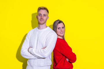 A man and a woman are standing next to each other on a yellow background