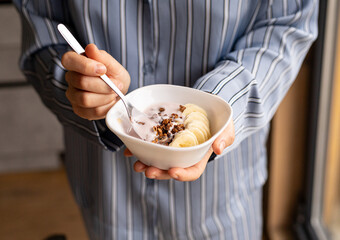 female hands, plate with granola, yogurt and bananas