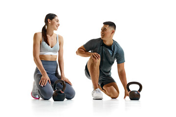 Portrait of man and woman taking break from their workout, kneeling on floor and smiling at each...