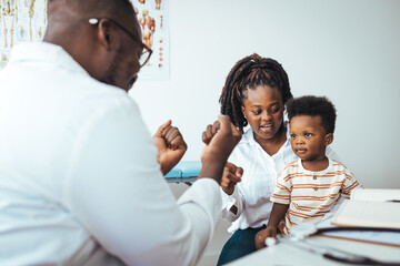 Smiling caring male pediatrician talk consult small boy patient at consultation in hospital with...