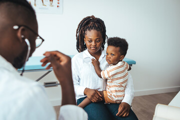 Smiling young African American mother with small 2s boy child son have consultation with caring...
