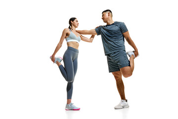 Man and woman stretching together, maintaining balance while holding their ankles against white...