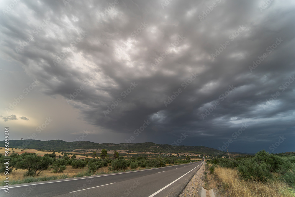 Sticker empty road (asphalt road) through yellowish fields. dramatic sky before rain and storm.