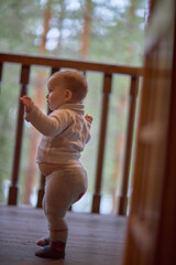 A baby stands confidently on a porch