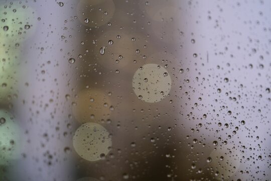 Window with rain drops illuminated by a yellow street light in the background