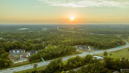 Aerial view of a winding highway surrounded by lush green trees.
