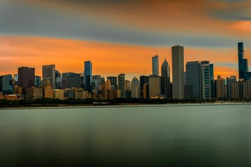 Scenic view of a cityscape against the sea at orange sunset