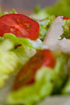 Extreme close up of a mixed salad with tomatoes and parmesan shavings

