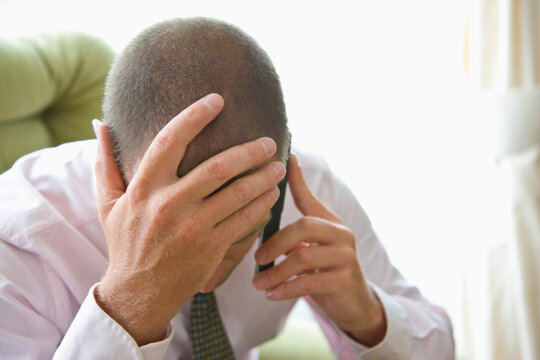 Close up of Businessman with Head in Hands Using Cell Phone
