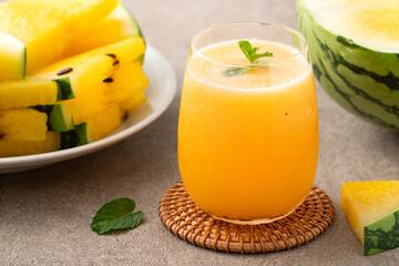 Fresh yellow watermelon juice in a glass cup on gray table background.