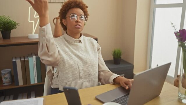 Depressed african american woman, sitting at home, chillingly points fingers like gun to head, enacting suicide gesture