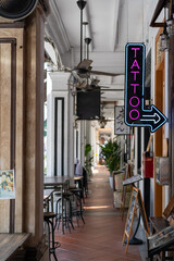 the entrance of a tattoo parlor with neon signage and chairs