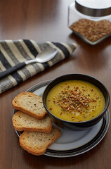 Pumpkin cream with garlic served with three pieces of toast in a black bowl
