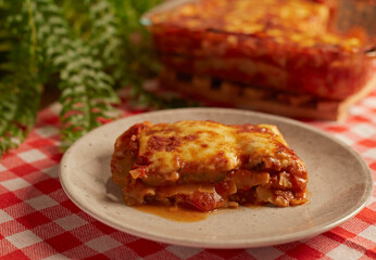 Lasagna in a plate on a checkered tablecloth