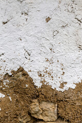 Weathered paint on a rough straw wall revealing natural texture over time