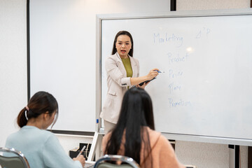 A woman is teaching a class in front of a whiteboard