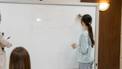 A woman is writing on a white board