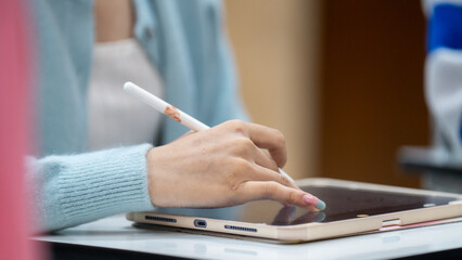 A woman is writing on a tablet with a white pen