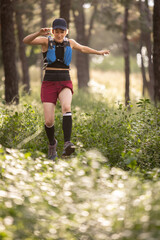 A woman is running through a forest with a backpack on her back