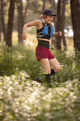 A woman is running through a forest wearing a black and blue life jacket