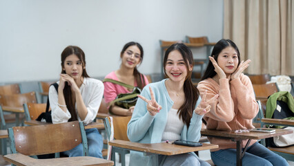 Four girls sitting in a classroom with one of them holding a peace sign