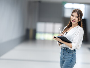 A woman is standing in a room and writing in a notebook