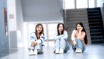 Fototapeta premium Three women are sitting on the floor in a hallway