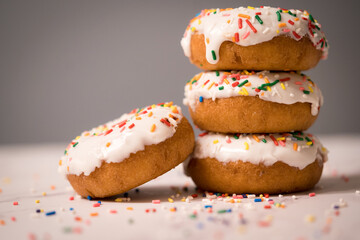 Closeup shot of stacked doughnuts with white icing and colorful sprinkles