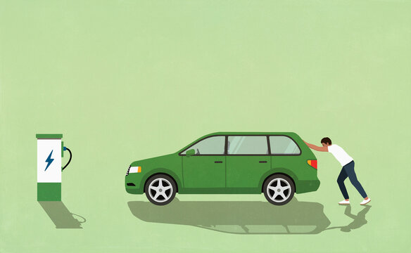 Man pushing green electric car toward electric charging station
